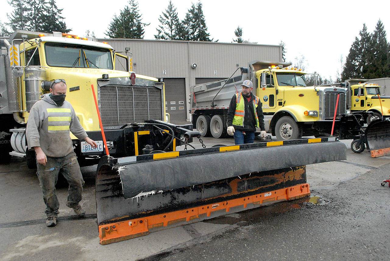 Driver Dustin Horn, left, and Clallam County Road Department Supervisor Adam Roening look over the equipment after hooking a plow to the front of a sand truck on Wednesday at the county maintenance yard in Port Angeles. (Keith Thorpe/Peninsula Daily News)