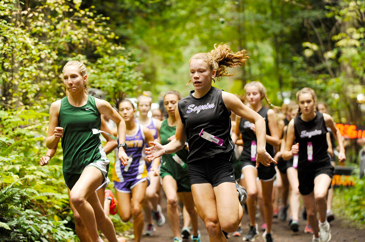 Port Angeles Lauren Larson, left, and Sequims Riley Pyeatt lead the pack at the beginning of a 2019 cross country race at Robin Hill Park. Prep runners can now run without masks at competitions after a change in state guidance. (Michael Dashiell/Olympic Peninsula News Group)