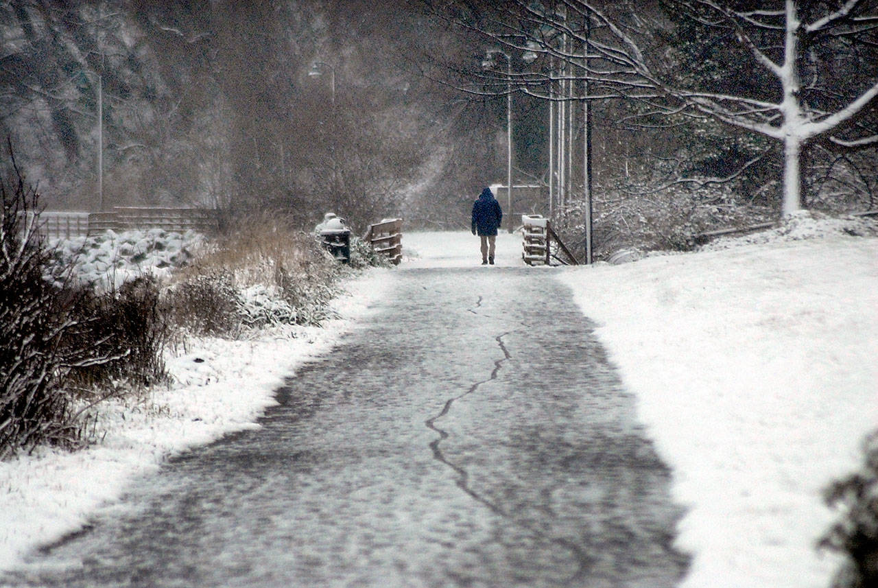 A pedestrian walks along a section of the Waterfront Trail east of downtown Port Angeles as a light snow falls on Thursday afternoon. Many areas of the North Olympic Peninsula were delivered with a taste of winter weather with additional snowfall expected across the region this weekend. (Keith Thorpe/Peninsula Daily News)