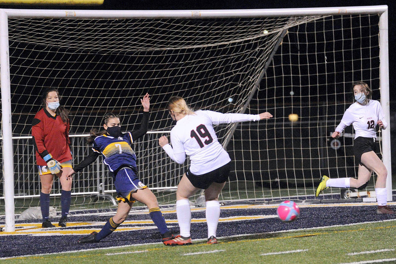 Forks’ Candida-Rose Sandoval, second from left, clears the ball away from the Spartans’ net between Ocosta players while Forks goalkeeper Katelynn Wallerstedt looks on. (Lonnie Archibald/for Peninsula Daily News)