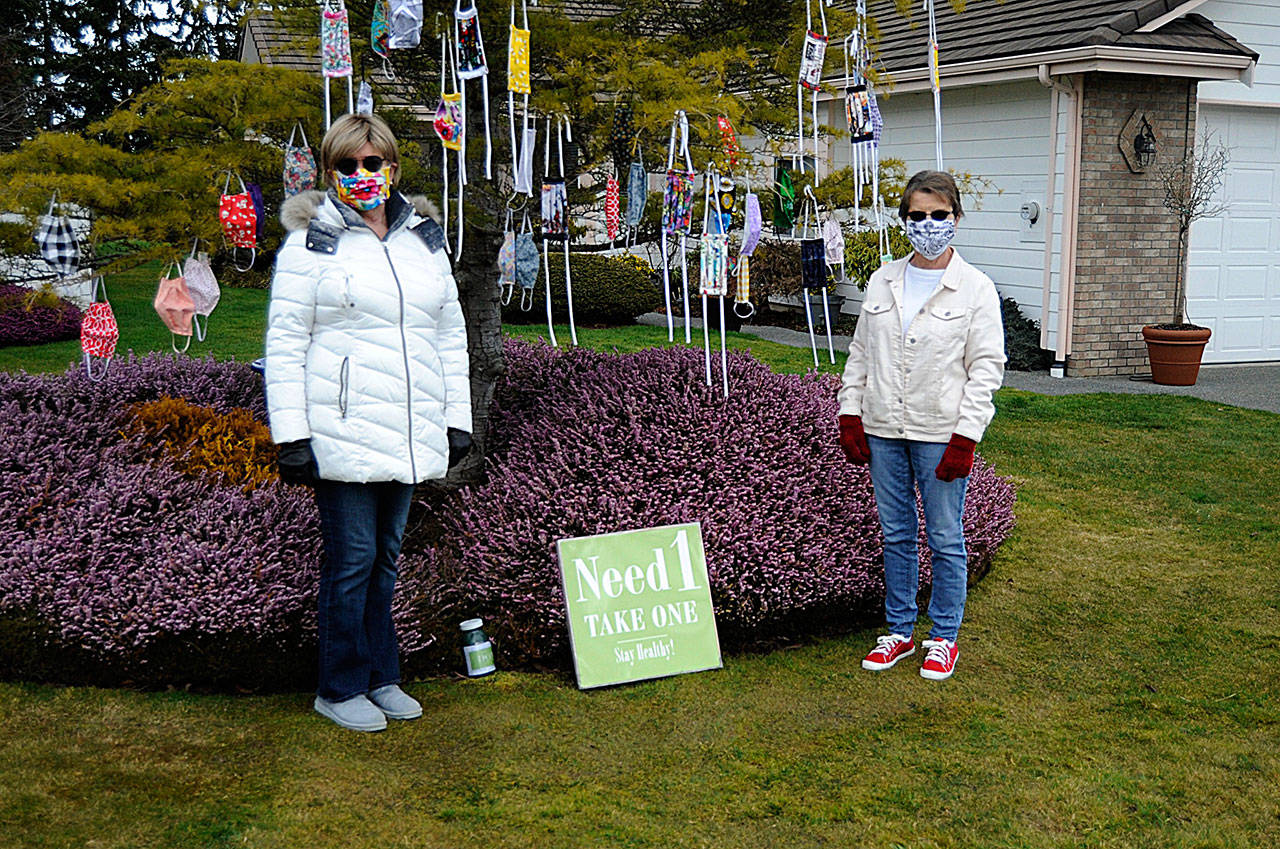 In Sunland North, Danette Bemis, left, and Kathy Tiedeman continue to hang cloth masks they make for free in Bemis’ front yard. Donations are accepted to help continue the effort, the friends said. (Matthew Nash/Olympic Peninsula News Group)