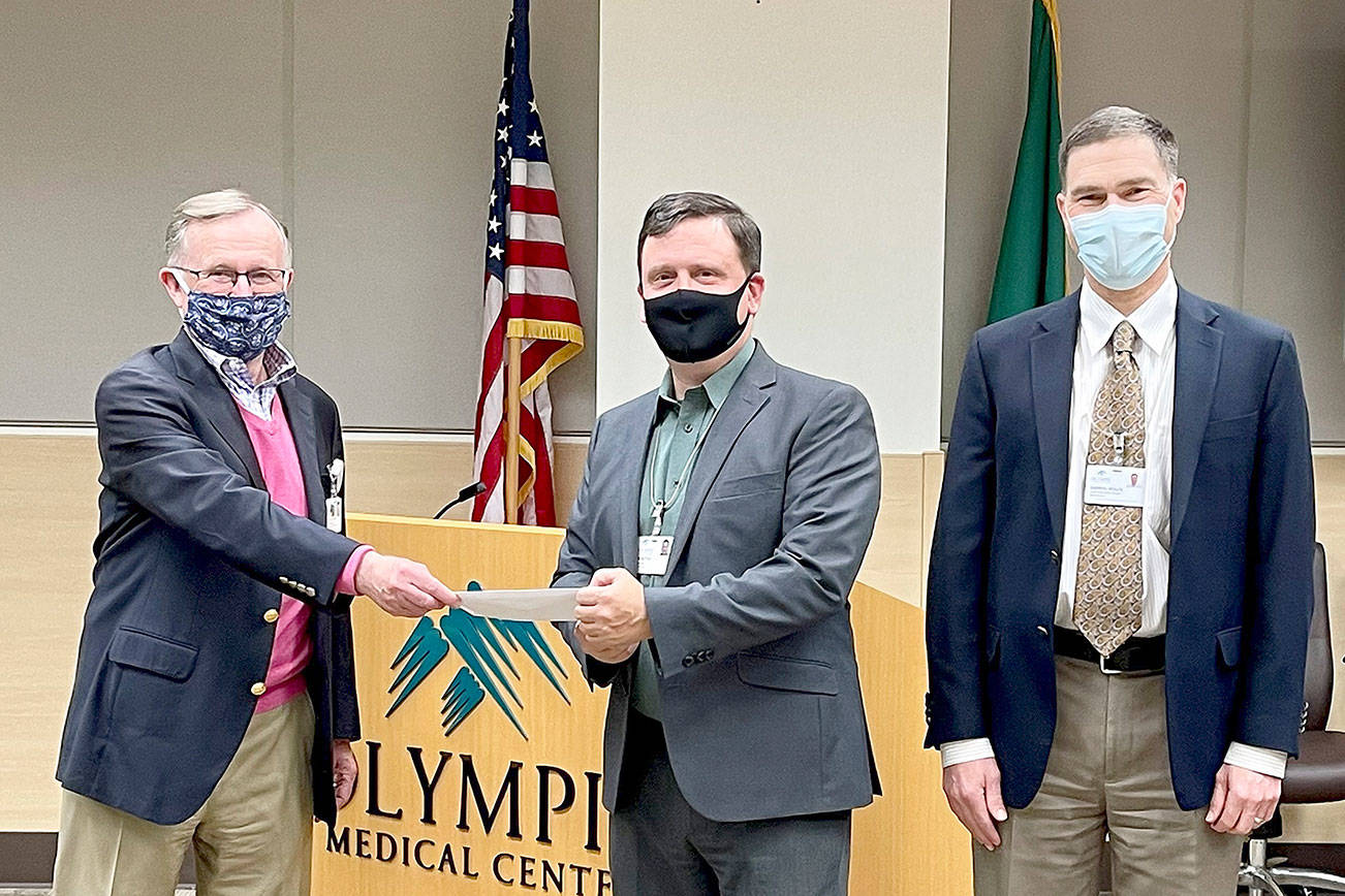 Bruce Skinner, Olympic Medical Center Foundation executive director, left, presents a check for $55,000 at last week’s OMC Commissioners meeting to Chair John Nutter, center, and OMC CEO Darryl Wolfe. (Submitted photo)