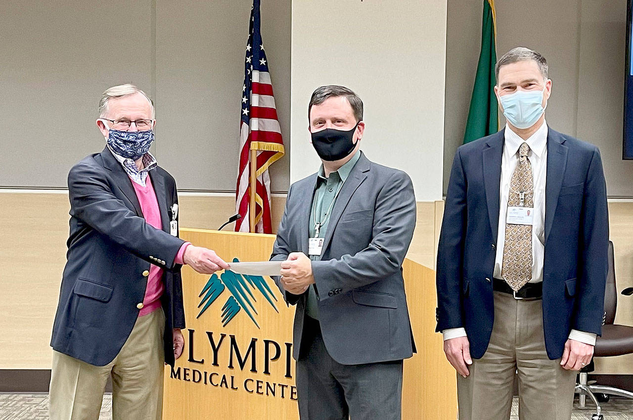Bruce Skinner, Olympic Medical Center Foundation executive director, left, presents a check for $55,000 at last week’s OMC Commissioners meeting to Chair John Nutter, center, and OMC CEO Darryl Wolfe. (Submitted photo)