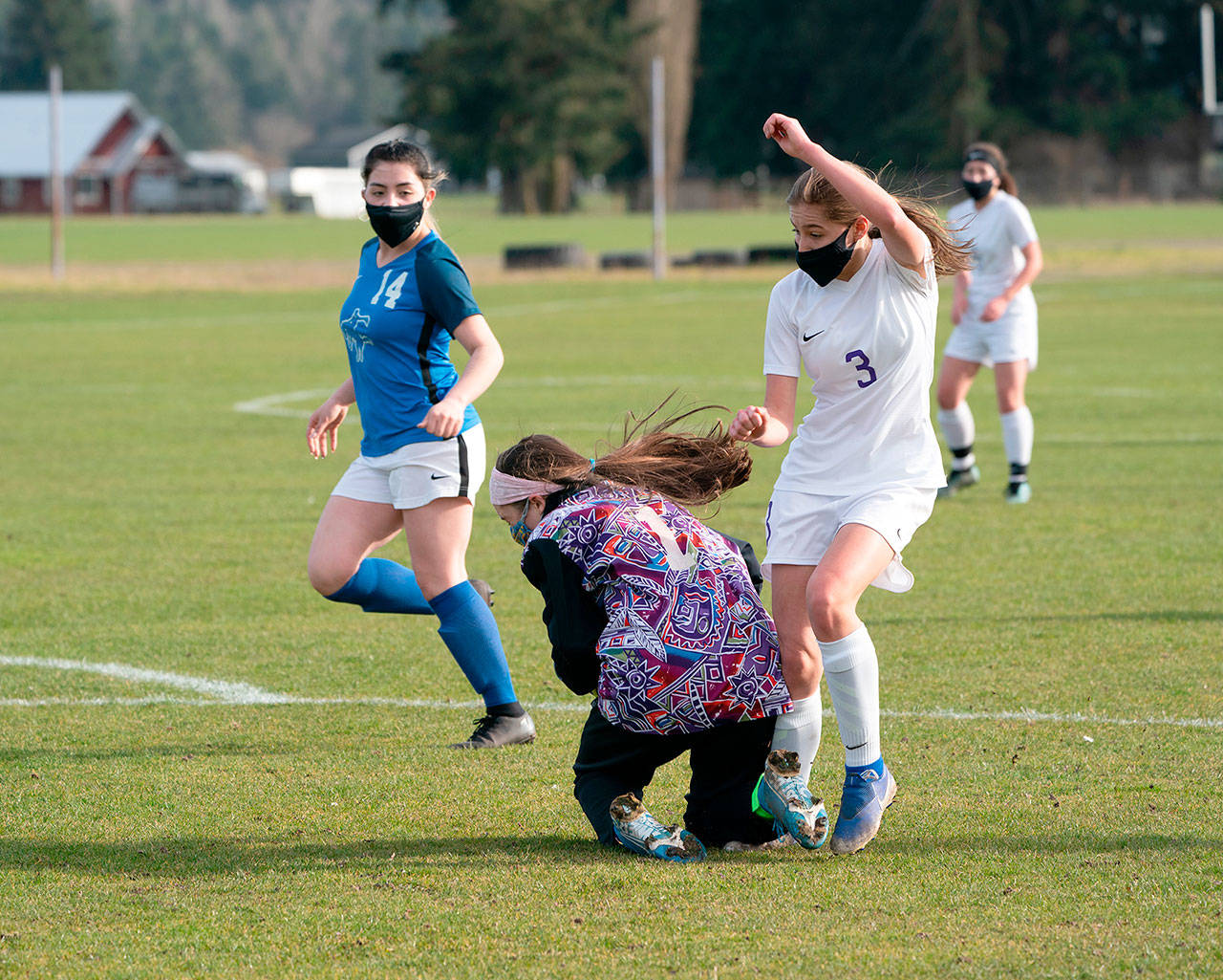 East Jefferson goalkeeper Sorina Johnston, center, saves a shot on goal but trips up Sequims Taryn Johnson while covering the ball as Stephanie Sanchez looks on during a game on Wednesday in Chimacum. (Steve Mullensky/for Peninsula Daily News)