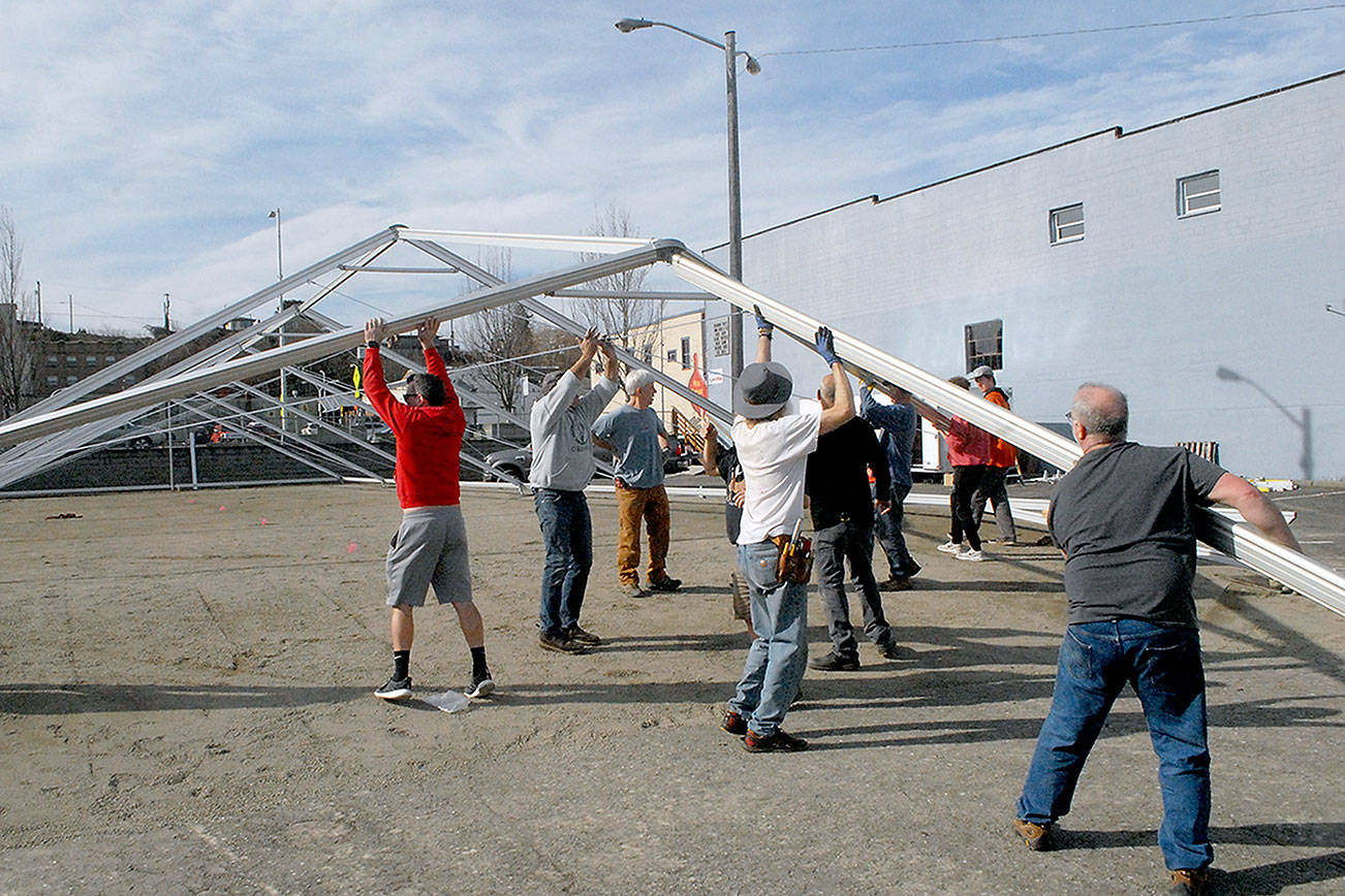 Keith Thorpe/Peninsula Daily News
Volunteers work on Saturday to erect an events tent that will cover a temporary ice skating rink, the centerpiece of the Port Angeles Ice Village. Normally held durring the winter months but delayed until spring due to COVID-19 restrictions, this year's skating will open on Friday and run through April 18 in a city-owned parking lot in the 100 block of West Front Street in downtown Port Angles. Skating will be open daily from 9 a.m. to 9 p.m.