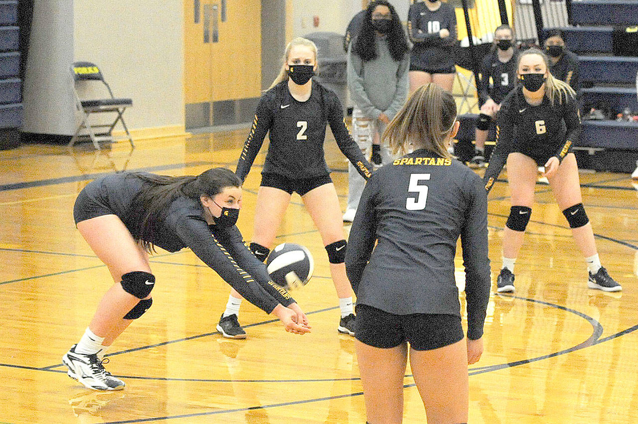 Kaidence Rigby of Forks digs while teammates Kadie Wood (2), Kray Horton (5) and Colbie Rancourt (6) look on. Forks defeated Rainier 3-0 and will advance in district play. (Lonnie Archibald/for Peninsula Daily News)