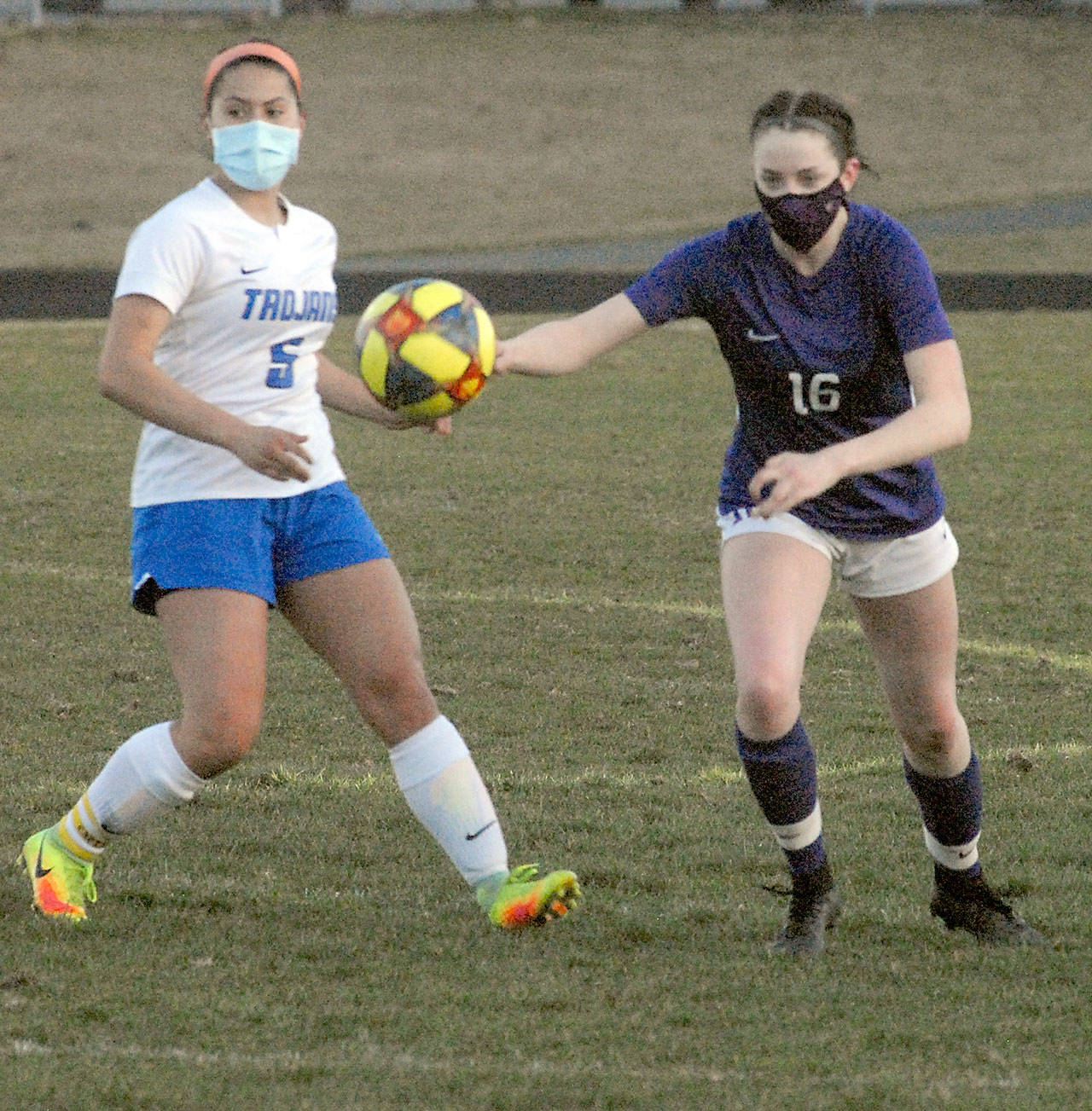 Olympic’s Alexis Valenzuela, left, and Sequim’s Abigail Schroeder chase after a loose ball during Tuesday night’s match at Sequim High School. (Keith Thorpe/Peninsula Daily News)