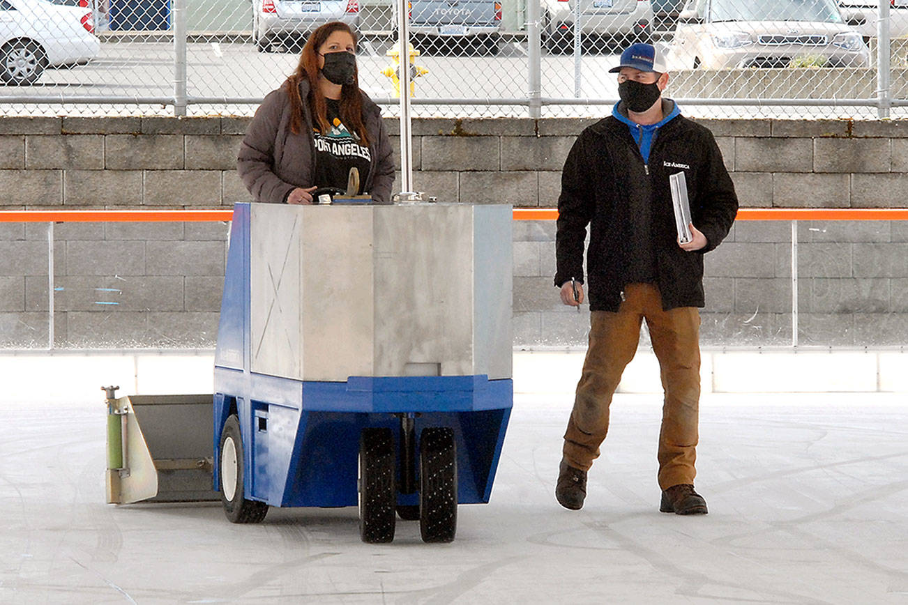 Leslie Robertson, events manager for the Port Angeles Regional Chamber of Commerce, gets a refresher course in operating an ice surfacing machine led by J.D. Uhls of Ice-America on Thursday in preparation for today’s opening of the Port Angeles Winter Ice Village. (Keith Thorpe/Peninsula Daily News)