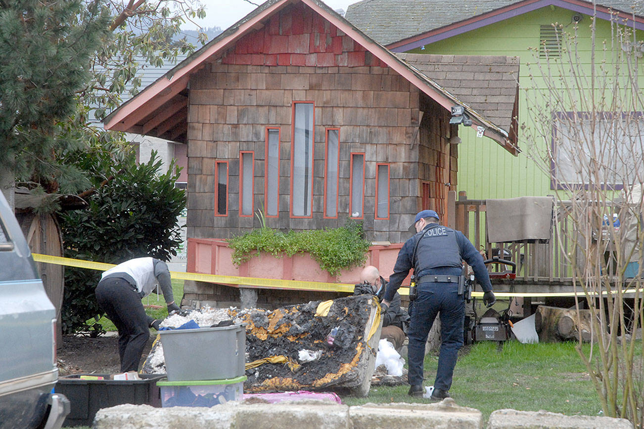 Keith Thorpe/Peninsula Daily News
Port Angeles police investigators examine evidence at the scene of a garage fire in the 100 block of East Fifth Street that authorities suspect was caused by arson.