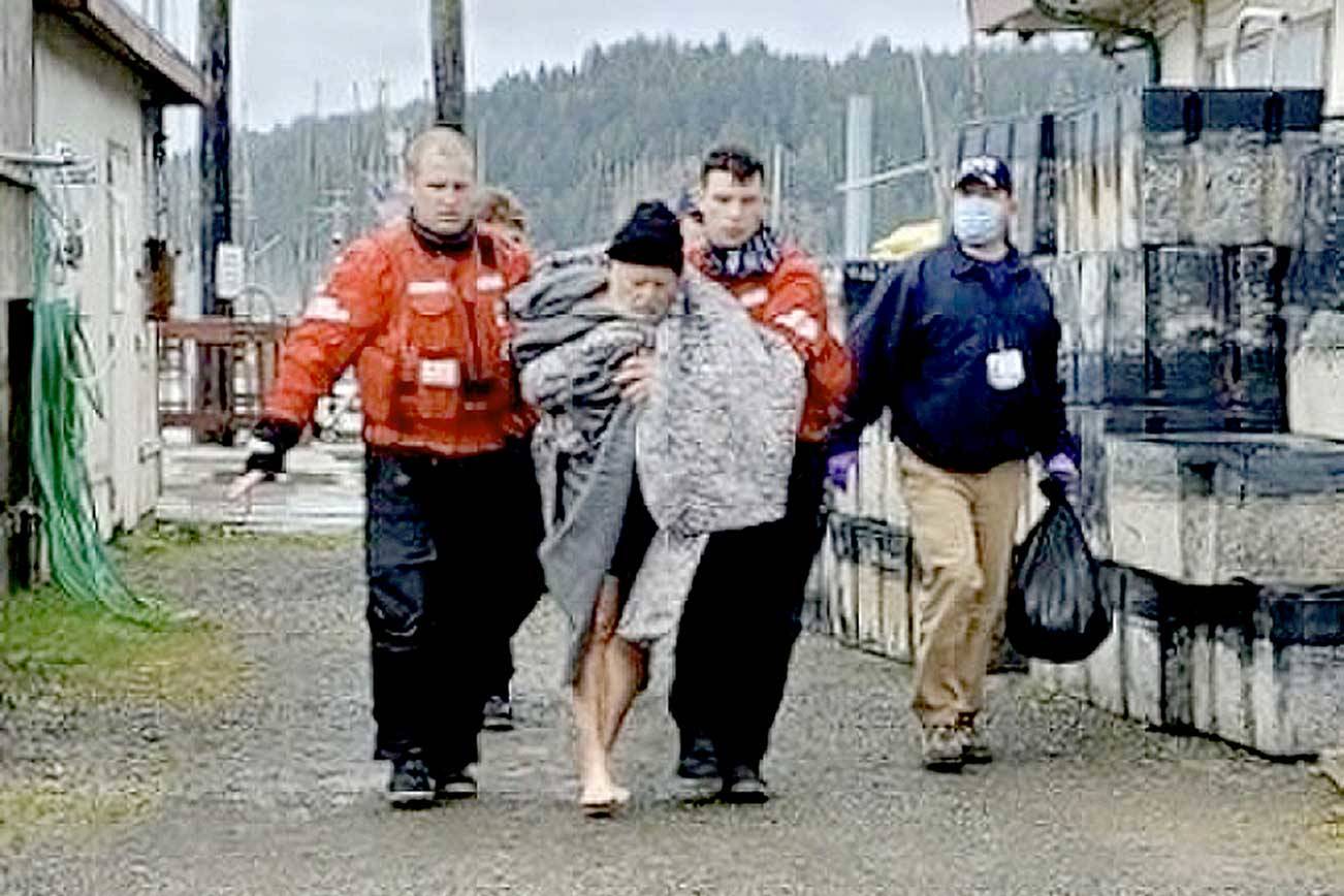 Members from Coast Guard Station Quillayute River help a man to an awaiting ambulance after the vessel he was in sank on Saturday 5 miles off the coast of La Push. None of the three men were wearing lifejackets. (U.S. Coast Guard photo by Station Quillayute River)