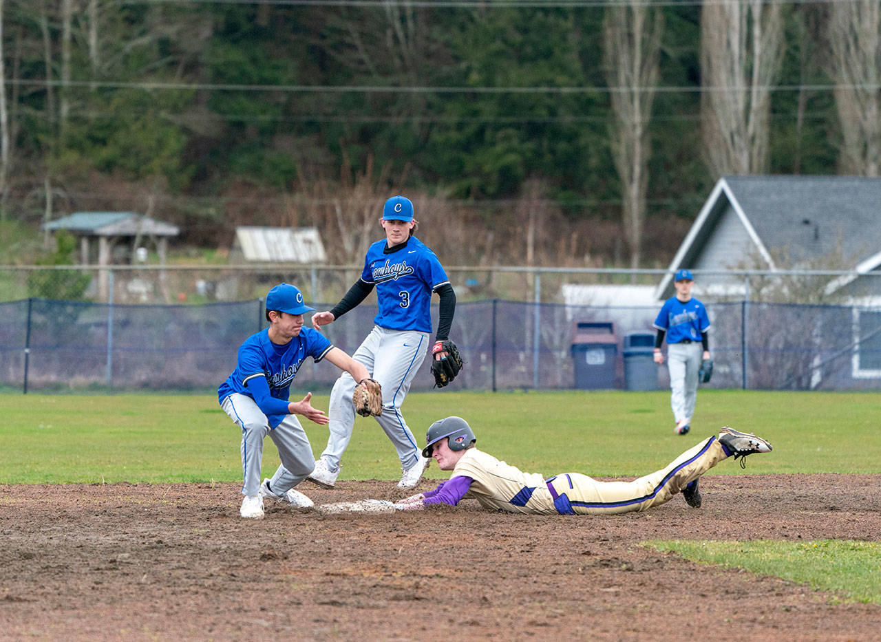 Sequim’s Ryan Porter slides safely into second under the glove of East Jefferson’s Hunter Cerna during a rainy Wednesday afternoon game played in Chimacum. Poised to back up the play is Marcus Ritch (3). (Steve Mullensky/for Peninsula Daily News)
