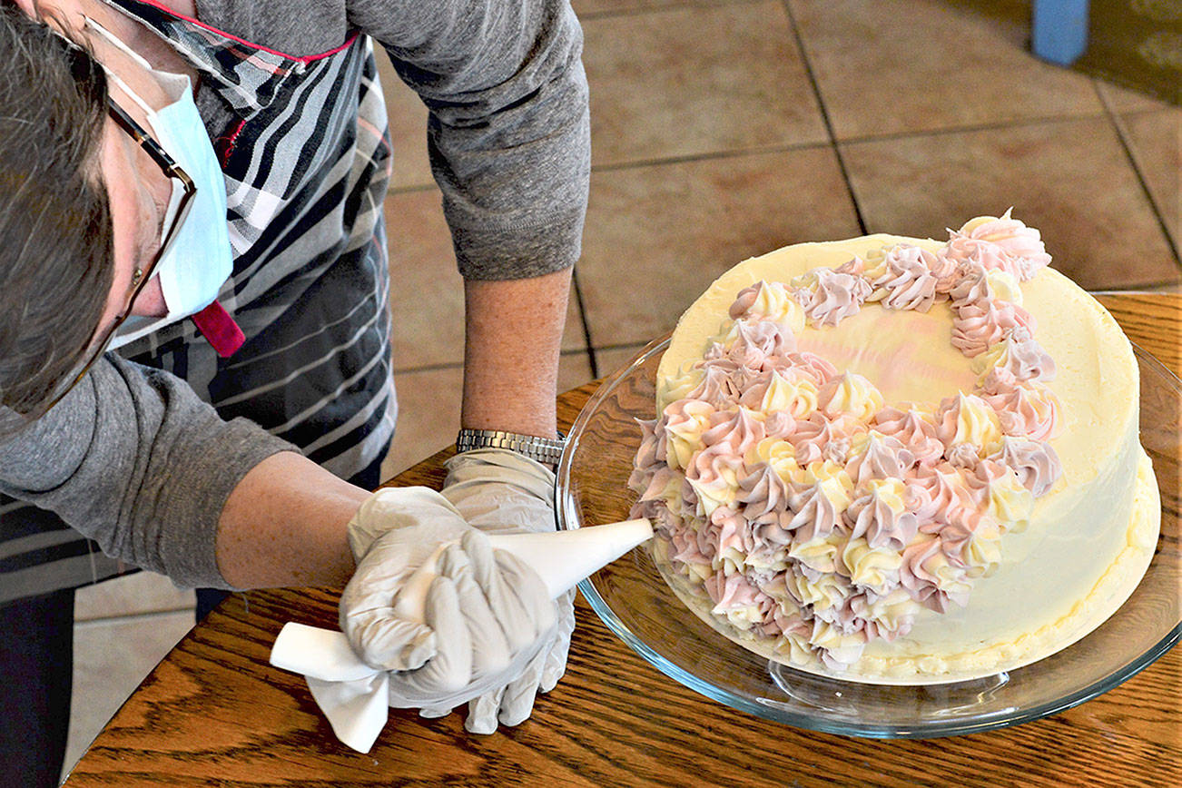 Volunteer Joan Coyne puts the icing on the cake for Jefferson County's Cake4Kids project earlier this month. Diane Urbani de la Paz/Peninsula Daily News