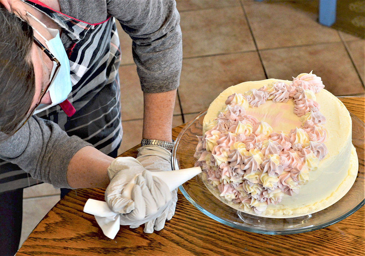 Volunteer Joan Coyne puts the icing on the cake for Jefferson Countys Cake4Kids project earlier this month. (Diane Urbani de la Paz/Peninsula Daily News)