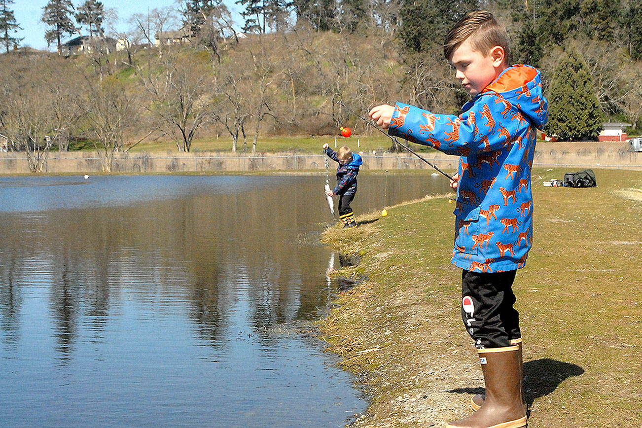 Weston Web, 6, prepares to cast a line at the children’s fishing pond at the Water Reuse Demonstration Site Next to Carrie Blake Park in Sequim on Wednesday as his brother, Bennet, 4, tends to a freshly caught fish. The Sequim boys were taking advantage of a mostly sunny day on the North Olympic Peninsula. (Keith Thorpe/Peninsula Daily News)