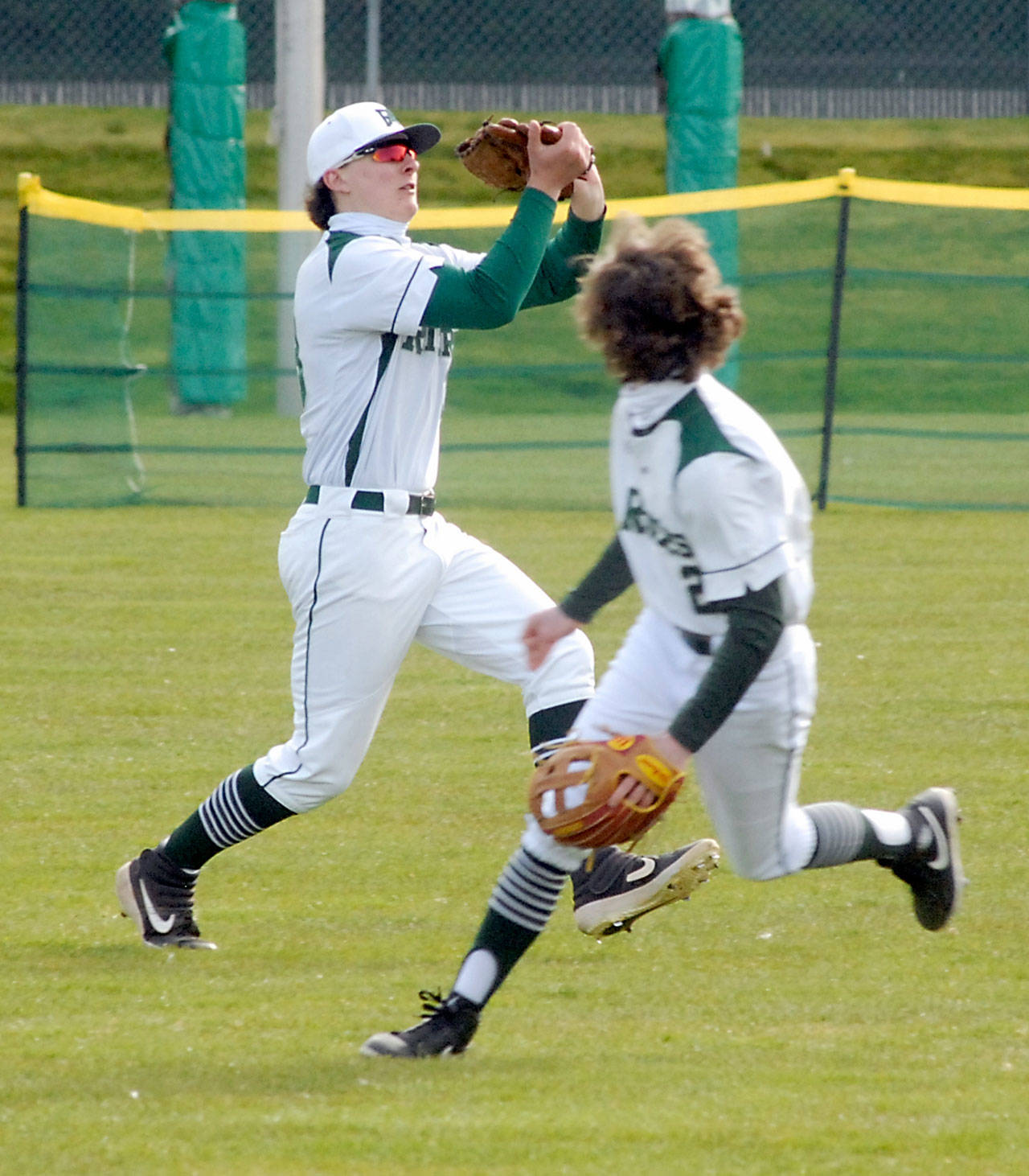 Keith Thorpe/Peninsula Daily News Port Angeles centerfielder Kamron Meadows, left, snags a fly ball as teammate Dru Clark backs away in the second inning against Olympic on Friday at Port Angeles Civic Field.