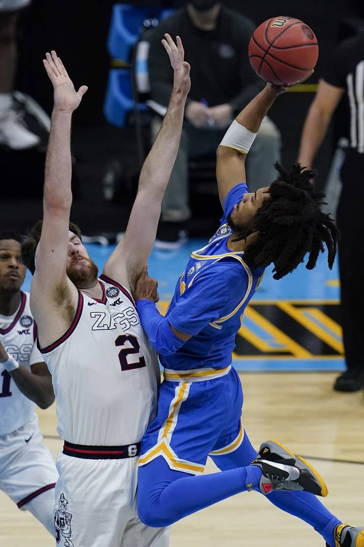 UCLA guard Tyger Campbell, right, shoots over Gonzaga forward Drew Timme (2) during the first half of a men’s Final Four NCAA college basketball tournament semifinal game, Saturday, April 3, 2021, at Lucas Oil Stadium in Indianapolis. (AP Photo/Michael Conroy)