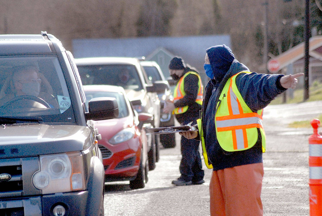 Vaccination clinic workiers Jack Harmon, front, and Jeramey Johnson check in motorists and direct traffic during Saturday’s clinic at Port Angeles High School. (Keith Thorpe/Peninsula Daily News)