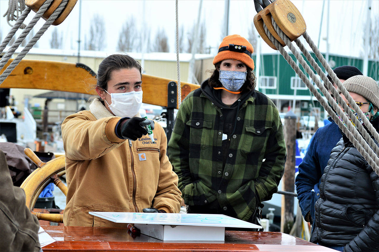 Adventuress Capt. Katelinn Shaw discusses steering and navigation with Northwest School of Wooden Boatbuilding students including Drew Harman, right, on board the schooner. (Diane Urbani de la Paz/Peninsula Daily News)