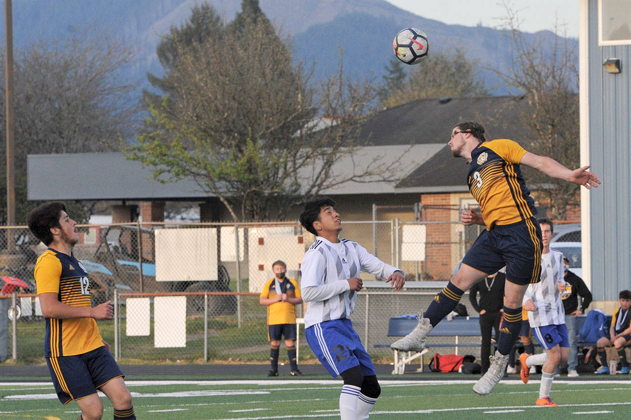 Forks defender Colton Duncan heads the ball away during the Spartans’ win over Elma while Spartan Luis Torres (12) looks on. (Lonnie Archibald/for Peninsula Daily News)
