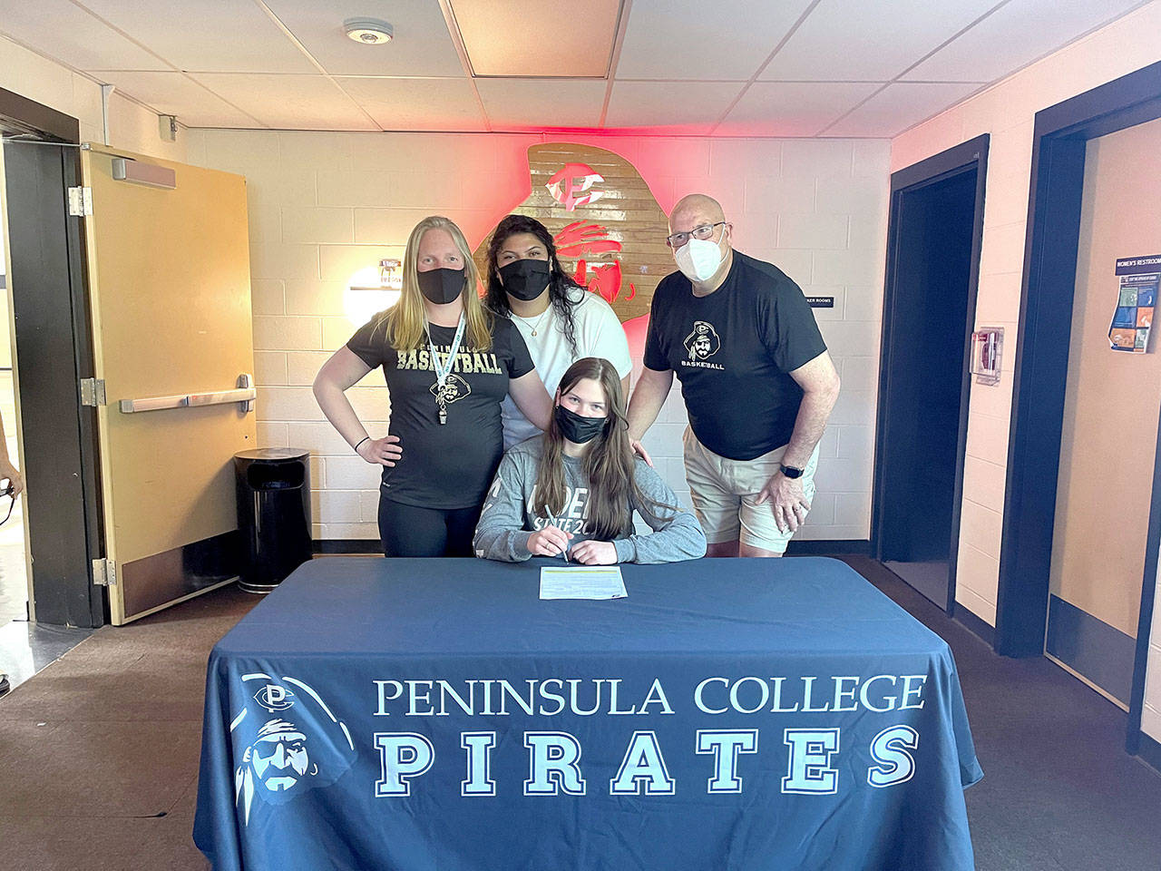 Port Angeles senior Myra Walker, seated, has signed a letter of intent to play basketball for Peninsula College. Walker is joined by from left, Peninsula head coach Alison Crumb and assistant coaches Gabi Fenumiai and Mike Knowles.