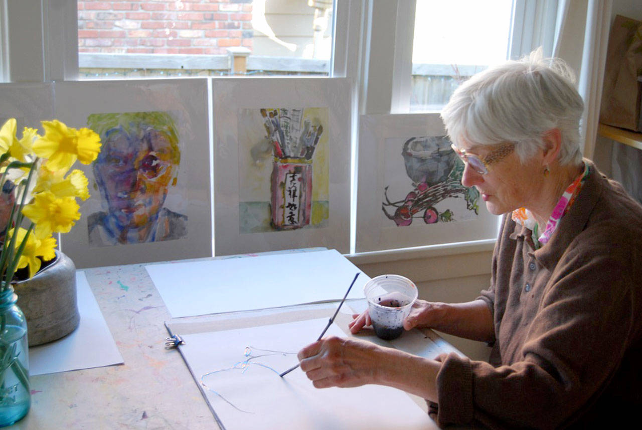 Nancy McFaul works on a new piece surrounded by finished images.