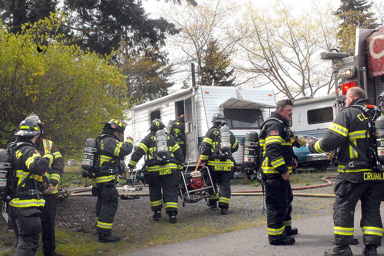 Clallam County District 2 firefighters work at the scene of a blaze that damaged a travel trailer at 2442 E. Highway 101, Space 25, of the Monroe Estates RV park in Port Angeles on Wednesday. District 2 Fire Chief Jake Patterson said his department was summoned after a passerby knocked on the door of a nearby trailer and informed that resident that the trailer was on fire, then left the scene. No one was at home when firefighters arrived, and no one was injured. Patterson said the cause of the blaze was unknown. Law enforcement authorities are investigating the blaze as possible arson. (Keith Thorpe/Peninsula Daily News)