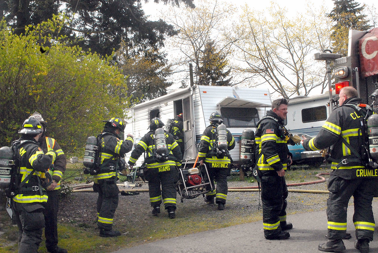 Clallam County District 2 firefighters work at the scene of a blaze that damaged a travel trailer at 2442 E. Highway 101, Space 25, of the Monroe Estates RV park in Port Angeles on Wednesday. District 2 Fire Chief Jake Patterson said his department was summoned after a passerby knocked on the door of a nearby trailer and informed that resident that the trailer was on fire, then left the scene. No one was at home when firefighters arrived, and no one was injured. Patterson said the cause of the blaze was unknown. Law enforcement authorities are investigating the blaze as possible arson. (Keith Thorpe/Peninsula Daily News)