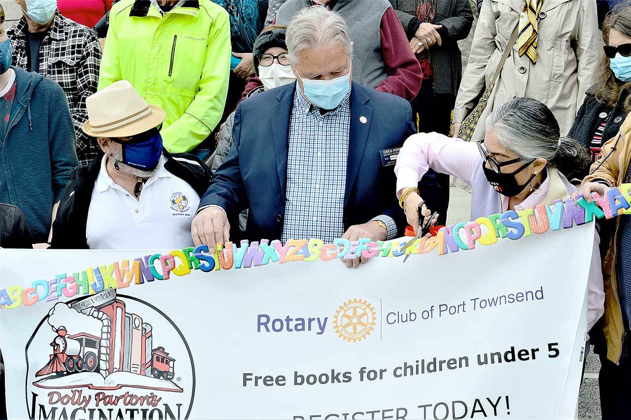 Port Townsend Mayor Michelle Sandoval cuts an alphabet ribbon to kick off the Dolly Parton Imagination Library registration project in Jefferson County on Monday. The Rotary Club of Port Townsend, which organized the campaign, was represented by District Governor Greg Horn, center, and club president Lee Hoffman. (Diane Urbani de la Paz/Peninsula Daily News)