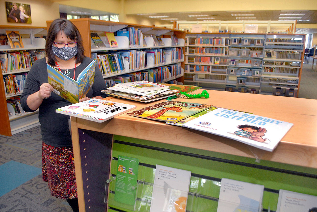 Jennifer Knight, youth services librarian at the Port Angeles Library, looks over a selection of books featured in Dolly Parton’s Imagination Library. (Keith Thorpe/Peninsula Daily News)