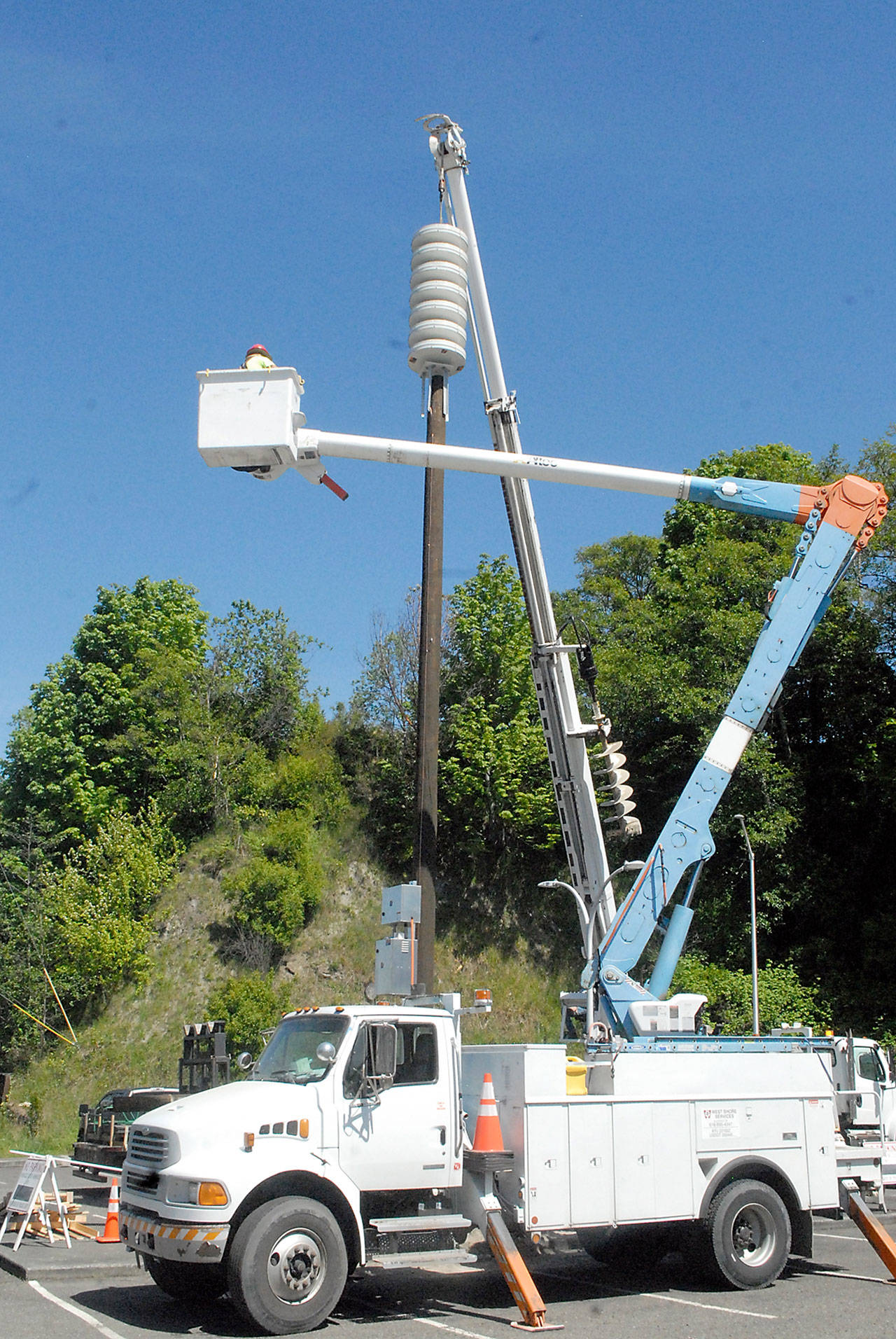 A crew hoists a new tsunami siren into place atop a pole located in the public parking lot at First and Lincoln streets in downtown Port Angeles. (Keith Thorpe/Peninsula Daily News)
