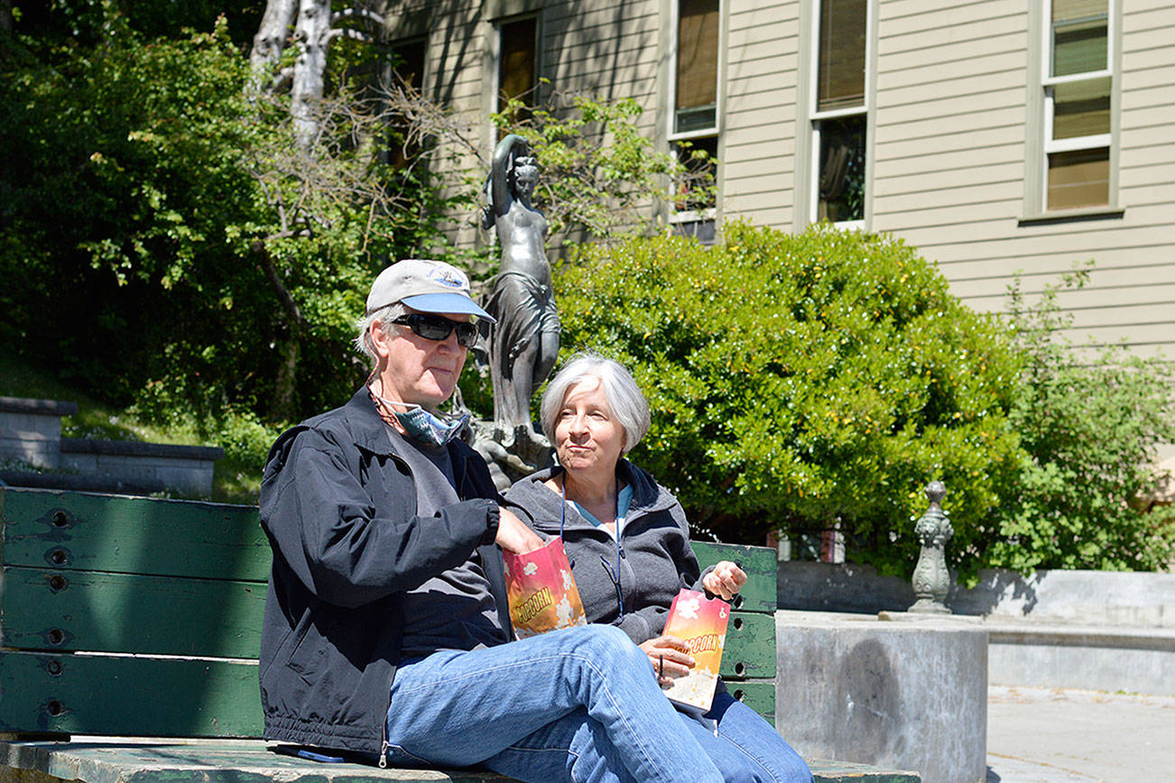 Jim Donaldson and Meg Snow enjoy popcorn from the Rose Theatre in downtown Port Townsend on Saturday. The theater has been popping corn on weekends for months while waiting for the day it can reopen. That day will come this summer.  Diane Urbani de la Paz/Peninsula Daily News