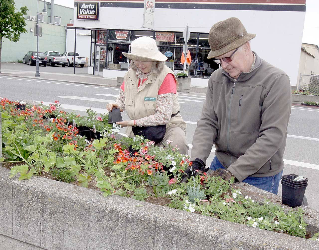 Volunteers Janet and Dale Russell of Port Angeles plant a variety of annual flowers along First Street near Country Aire as part of the Big Spring Spruce Up. The Port Angeles Chamber of Commerce hosted a flower planting party early Sunday. Dozens of volunteers planted annual flowers in the 20 triangle-shaped planters along First and Front streets in the downtown area. (Dave Logan/for Peninsula Daily News)