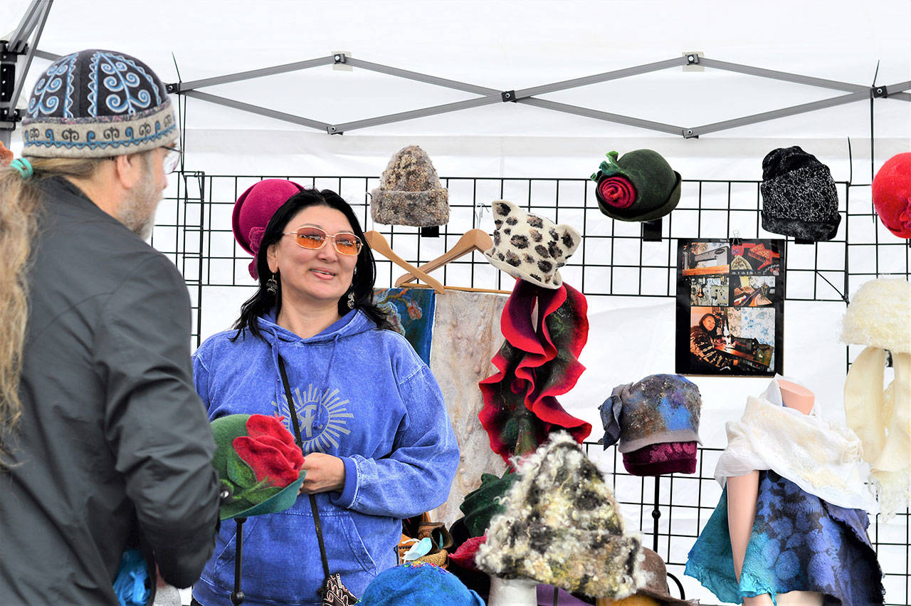 Shawn Woodyard of Port Angeles talks with Juan de Fuca Festival street fair vendor Cholpon Djumabaeva, who, with her husband Jon, runs Kyrgyz-Konnection of Gig Harbor. (Diane Urbani de la Paz/Peninsula Daily News)