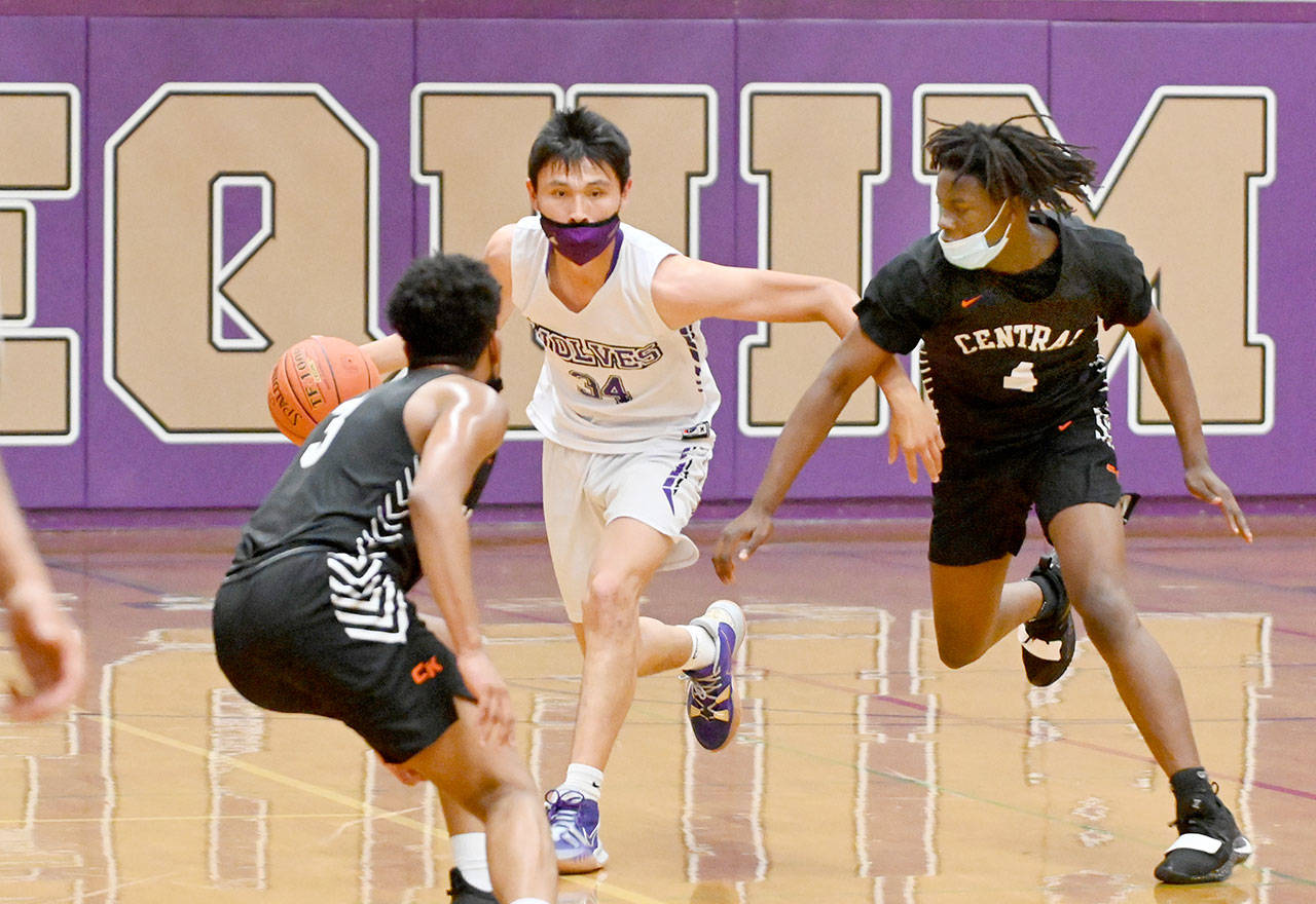 Sequim’s Isaiah Moore dribbles between two Central Kitsap defenders during the Wolves’ 72-49 loss Wednesday. Moore had 19 points and eight rebounds to lead Sequim. (Michael Dashiell/Olympic Peninsula News Group)