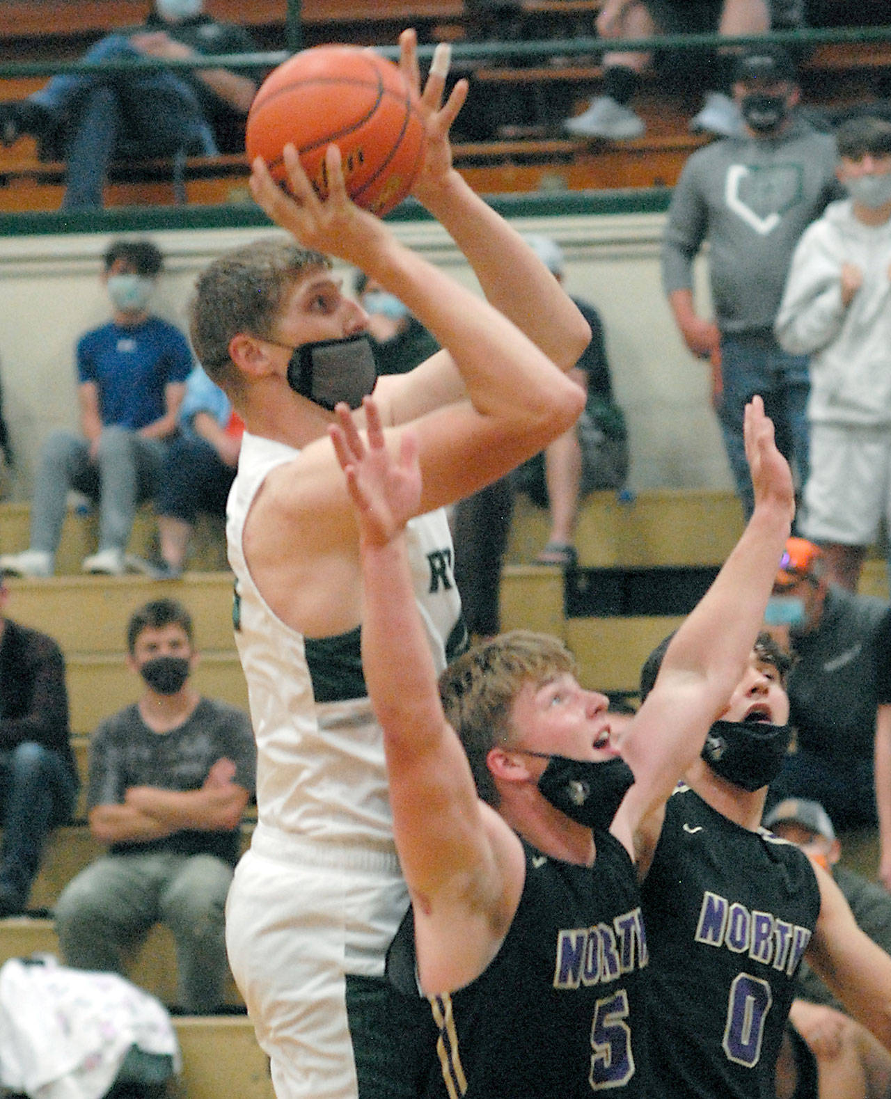 Keith Thorpe/Peninsula Daily News Port Angeles’ John Vaara aims for the basket over the heads on North Kitsap’s Colton Bower, front, and Johny Olmsted on Thursday at Port Angeles High School.