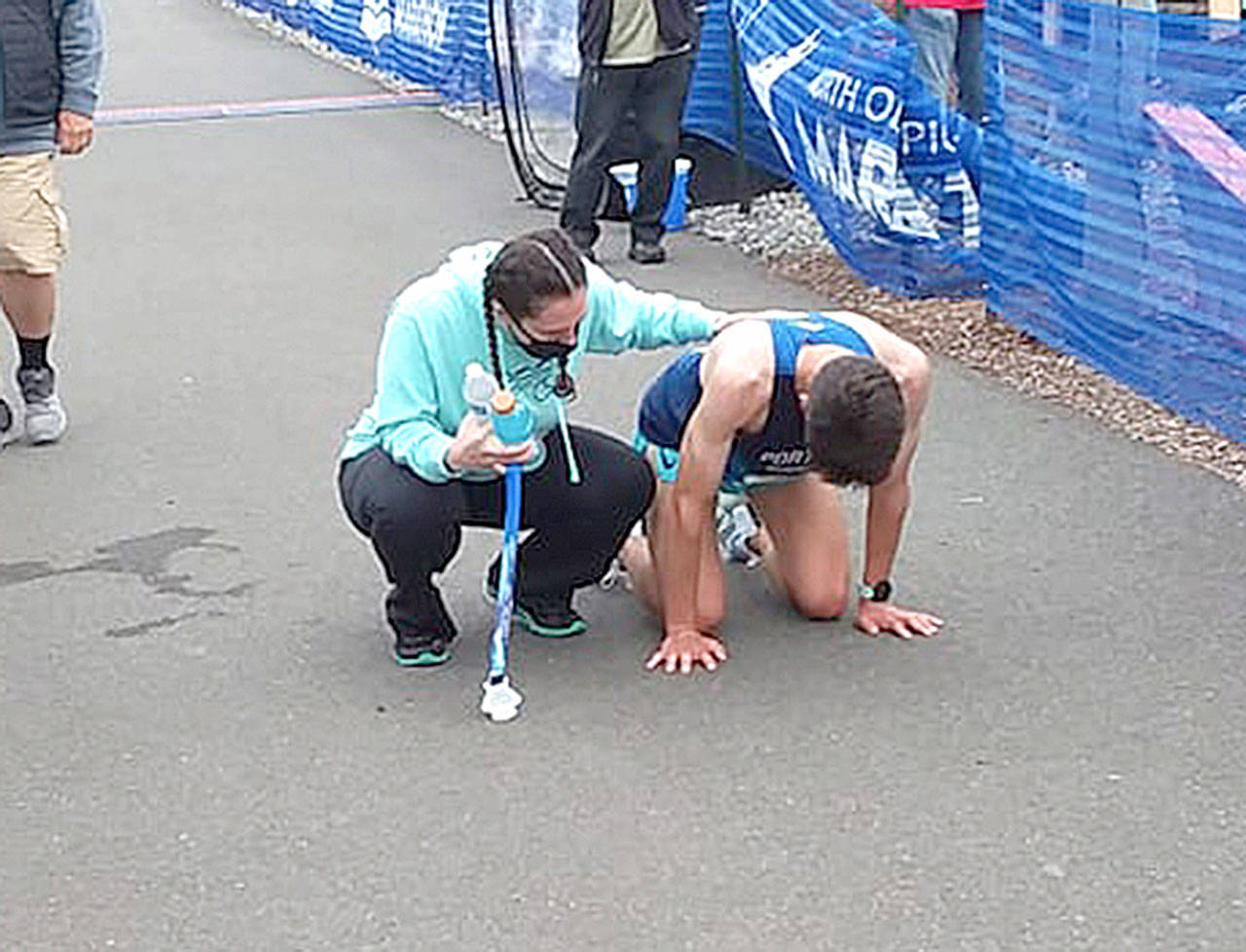 Adam Klein of Tualatin, Ore., collapses after winning the North Olympic Discovery Marathon and is helped by marathon volunteer Kaitlin Alderson. (Pierre LaBossiere/Peninsula Daily News)