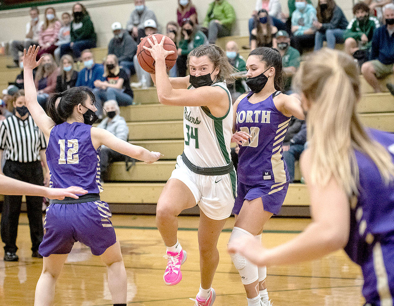 Jaida Wood of Port Angeles (34) drives around the defense of North Kitsap’s Mia McNair in Monday night’s Olympic League playoff win for the Roughriders. (Jesse Major/for Peninsula Daily News)