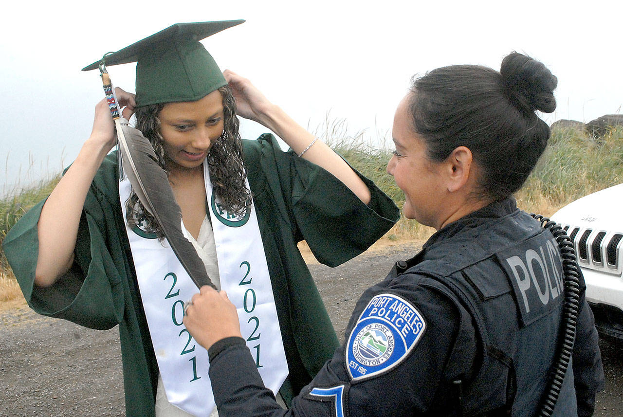 Port Angeles High School graduate Kayanna Cordero gets assistance with her mortarboard from her mother, Port Angeles police Resource Officer Swift Sanchez, prior to the start of Friday’s Senior Parade from Ediz Hook to the area of Port Angeles High School. (Keith Thorpe/Peninsula Daily News)