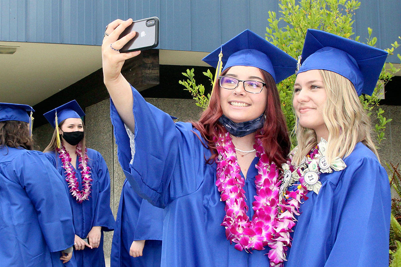 Tia Berson, left, and Chloe Mandeville take a selfie just before their march onto the field at Crescent High School for graduation ceremonies Saturday afternoon. There were 12 members of Crescent's Class of 2021: Katelyn Baar, Brendan Bergstrom, Tia Berson, James Bruch, Ashley Girard, Lael Harris, Justin Irving, Zach Irving, Darren Lee, Chloe Mandeville, Wyatt Mattix and Colton O’Neel. There was no designated valedictorian this year. (Dave Logan/for Peninsula Daily News)
