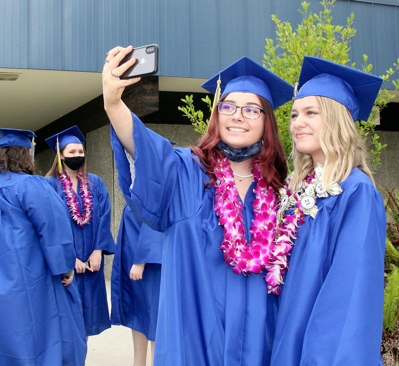 Tia Berson, left, and Chloe Mandeville take a selfie just before their march onto the field at Crescent High School for graduation ceremonies Saturday afternoon. There were 12 members of Crescent’s Class of 2021: Katelyn Baar, Brendan Bergstrom, Berson, James Bruch, Ashley Girard, Lael Harris, Justin Irving, Zach Irving, Darren Lee, Mandeville, Wyatt Mattix and Colton O’Neel. There was no designated valedictorian this year. (Dave Logan/for Peninsula Daily News)