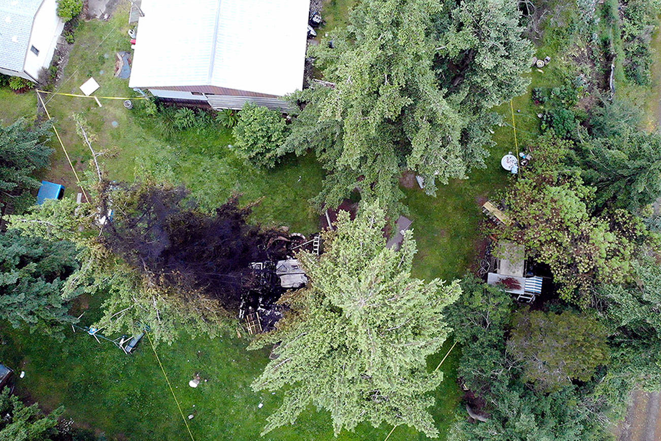 Officials with Jefferson County Sheriff’s Office, Washington State Patrol and the FBI investigate the site of an explosion on Tuesday night in Port Hadlock. The explosion blew off a man’s arm and burned his granddaughter. The blast and subsequent fire destroyed an outbuilding and damaged the trees and grass around it. (Photo courtesy of Jefferson County Sheriff’s Office)