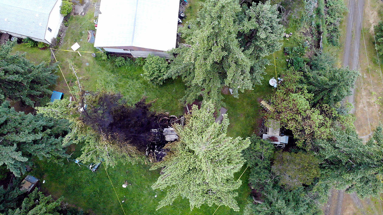 Officials with Jefferson County Sheriff’s Office, Washington State Patrol and the FBI investigate the site of an explosion on Tuesday night in Port Hadlock. The explosion blew off a man’s arm and burned his granddaughter. The blast and subsequent fire destroyed an outbuilding and damaged the trees and grass around it. (Photo courtesy of Jefferson County Sheriff’s Office)