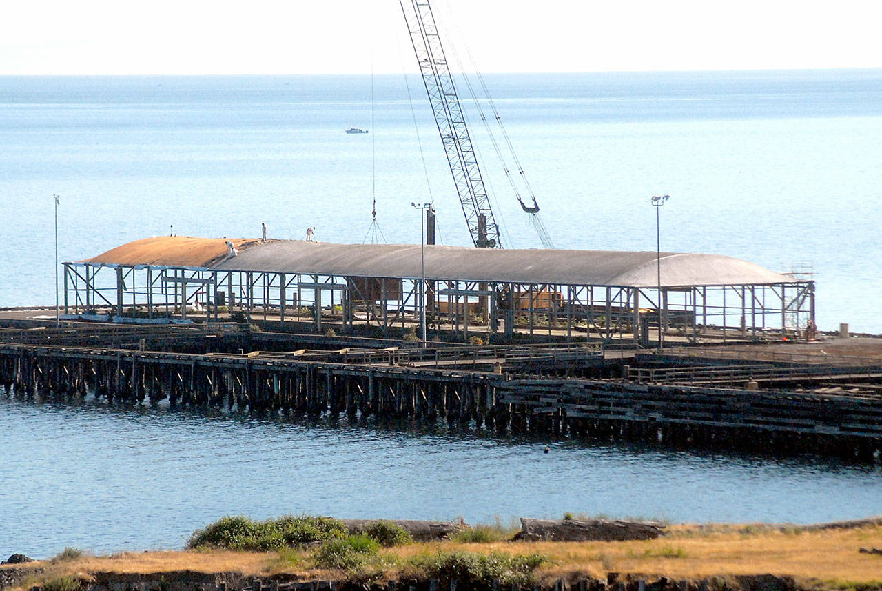 Crews work on Thursday to dismantle the loading dock at the site of the former Rayonier pulp mill in Port Angeles. Workers began removing about 800 concrete dock panels this week as a step toward dismantling the 6-acre pier at the former Rayonier property 2 miles east of downtown Port Angeles. The target date for completion is July, while more than 5,000 creosote-treated pilings will not be taken out at least until 2023 as part of the overall environmental cleanup of the 75-acre former industrial site’s uplands and adjacent harbor waters, a process overseen by the state Department of Ecology and paid for by property owner Rayonier Advanced Materials. (Keith Thorpe/Peninsula Daily News)