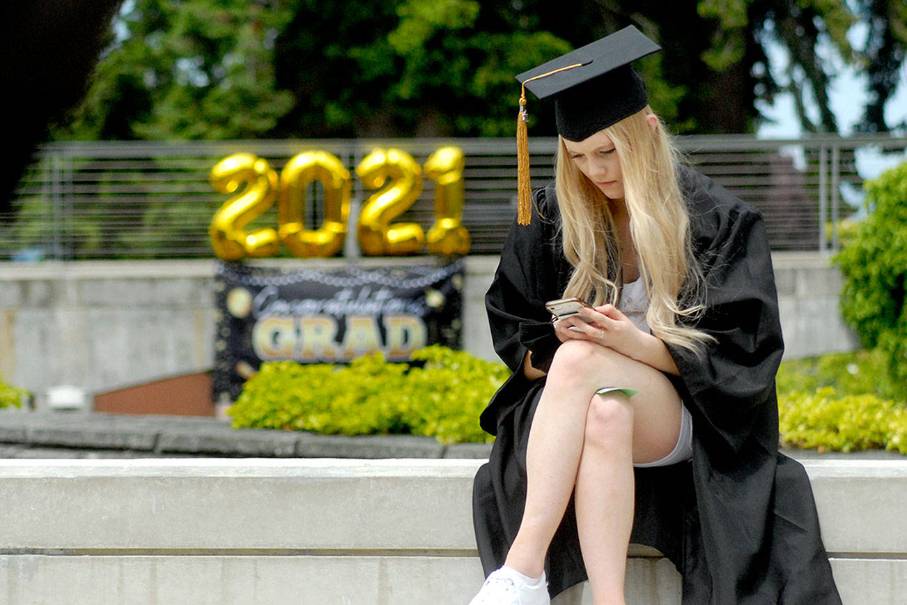 Keith Thorpe/Peninsula Daily News
Peninsula College graduate Mackenzie Jay of Sequim looks at her cellphone in Pirate Square prior to the beginning of Saturday's ceremony to award associate of arts degrees on the Port Angeles campus. A total of 413 students were qualified to receive degrees and certificates as part of the Class of 2020 and 2021.