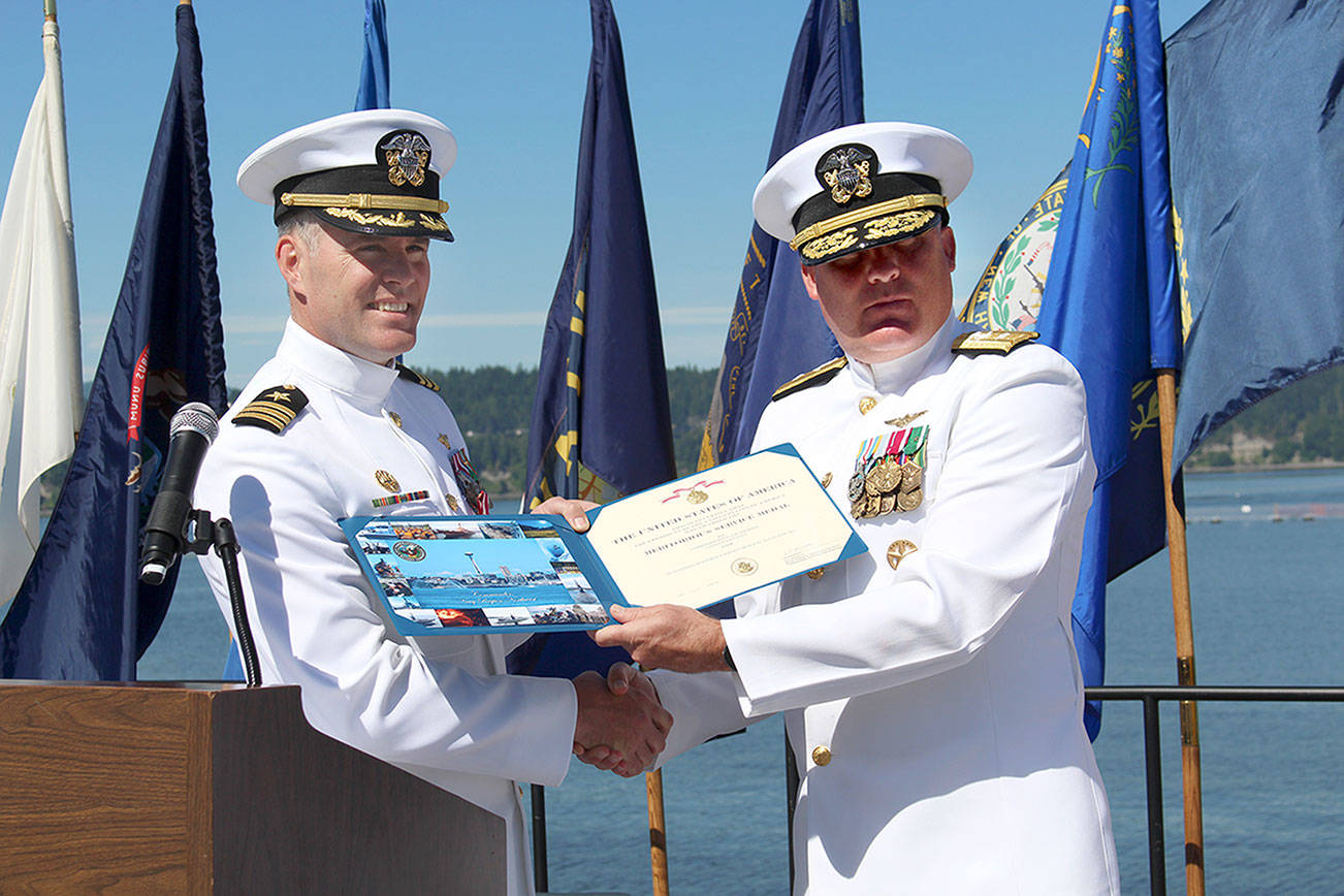 Commander Donald Emmerson, left, receives the Meritorious Service Medal from Rear Admiral Brad Collins, commander of Navy Region Northwest, during Naval Magazine Indian Island’s Change of Command ceremony on Thursday. Emmerson’s role of commanding officer is now filled by Commander Andrew Crouse. (Zach Jablonski/Peninsula Daily News)