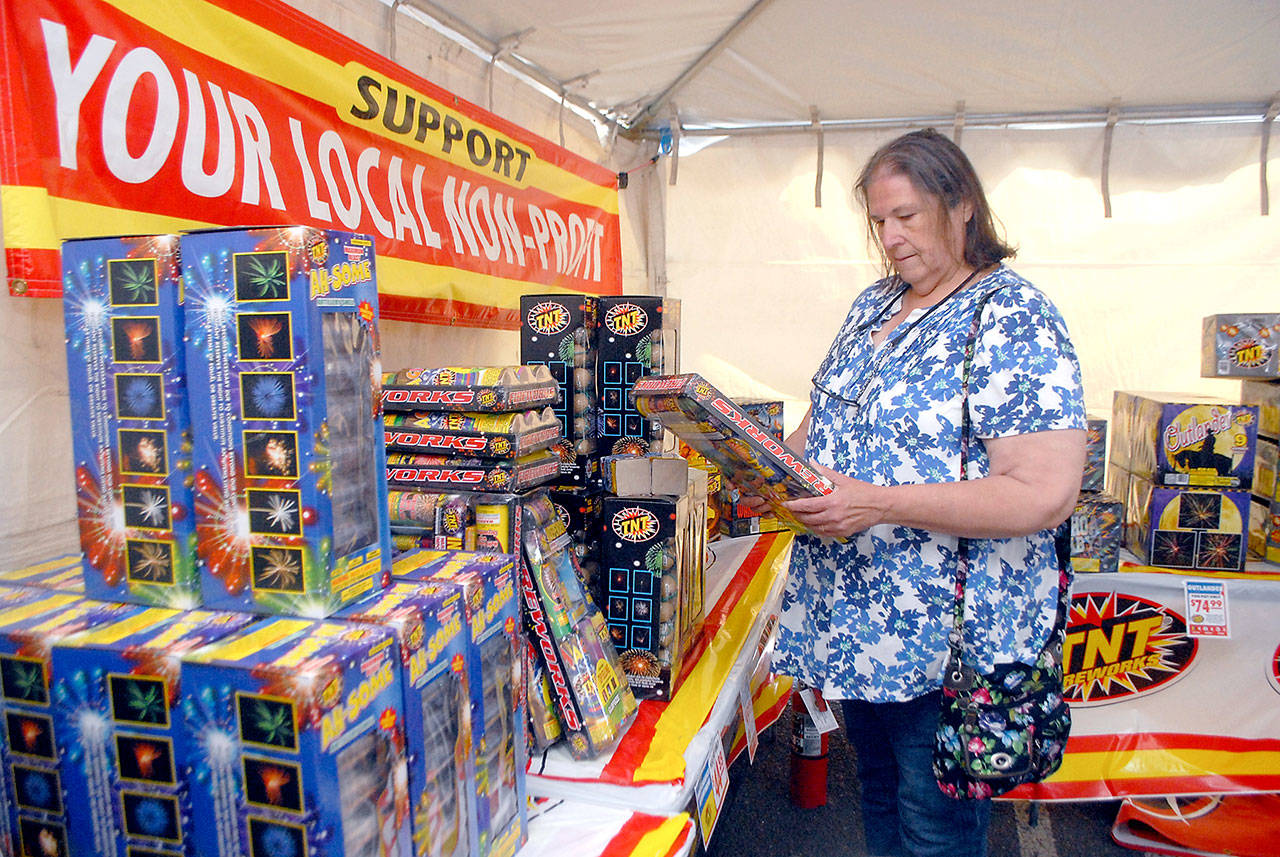 Paula Walters of Port Angeles looks over a selection of fireworks on display on Tuesday at a fireworks tent operated by the Clallam County Amateur Radio Club at the Safeway shopping plaza on U.S. Highway 101 east of Port Angeles. (Keith Thorpe/Peninsula Daily News)