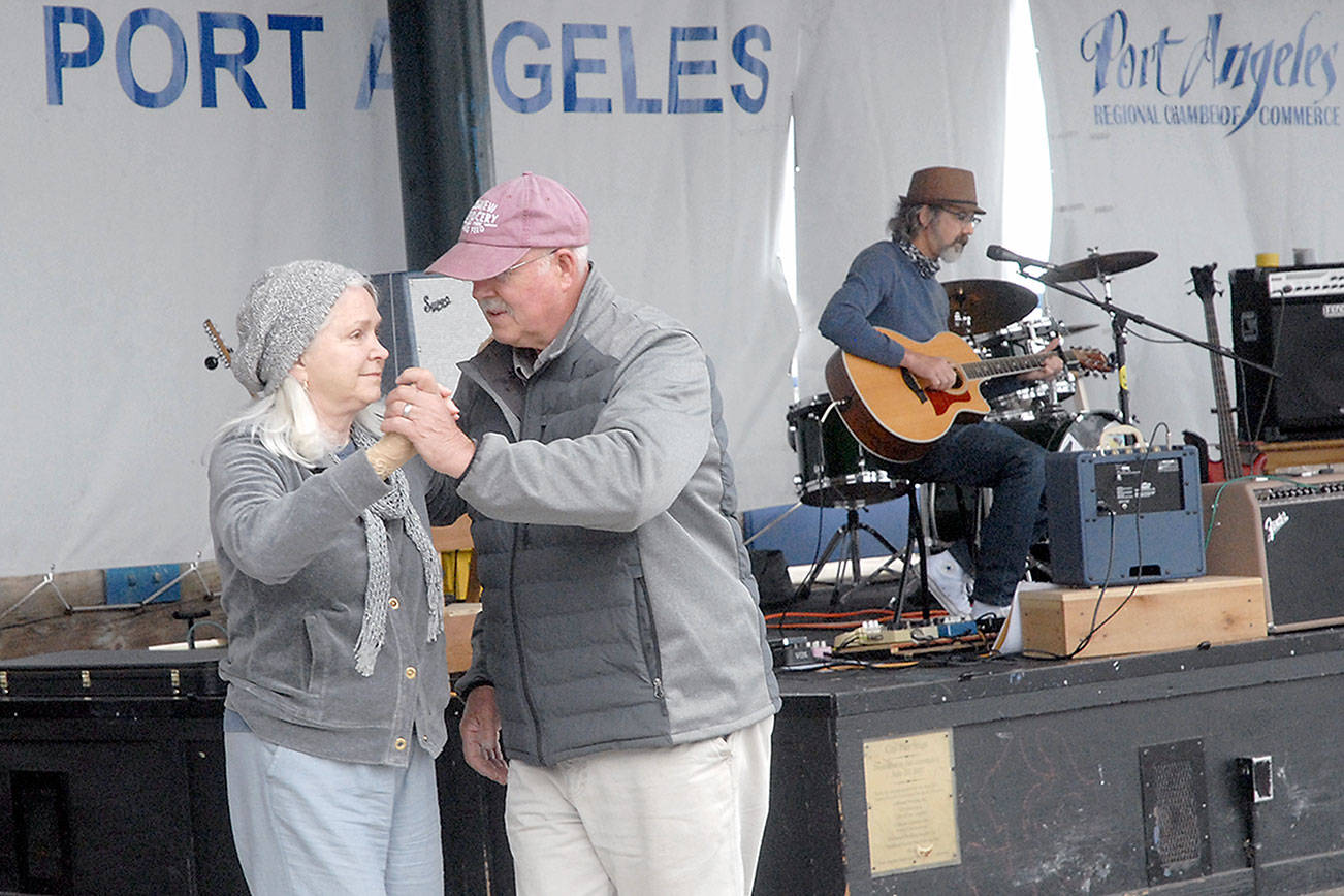 Ann and Steve Johnson of rural Port Angeles dance to the music of John Huard at the season opener of the Concerts on the Pier music series on Wednesday at Port Angeles City Pier. Huard was the opening act for a garage surf music performance by Port Angeles-based AntBath, signaling a return to live music after the weekly series was put on hiatus in 2020 by COVID-19. Abakis will perform vintage country music at the next performance, set for 6 p.m. on July 14. Concerts on the Pier are presented by the Juan de Fuca Foundation, Elwha River Casino, the Port Angeles Parks and Recreation Department and the Peninsula Daily News. Sequim offers free weekly concerts in its Music Where You Park series every Tuesday through July 27. (Keith Thorpe/Peninsula Daily News)