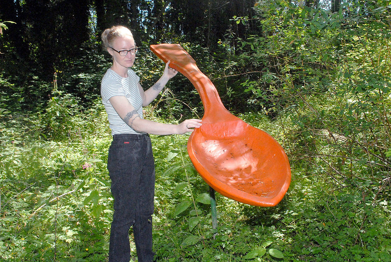 Sarah Jane, gallery and program director of the Port Angeles Fine Arts Center, admires “Spoonful” by Lucy Congdon Hanson, a featured art installation on Saturday’s guided tour of Webster’s Woods Sculpture Park. (Keith Thorpe/Peninsula Daily News)