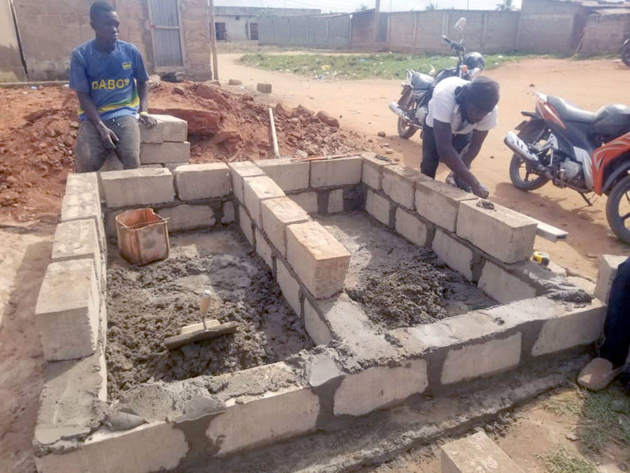 Workers build a composting toilet for a family in Togo.