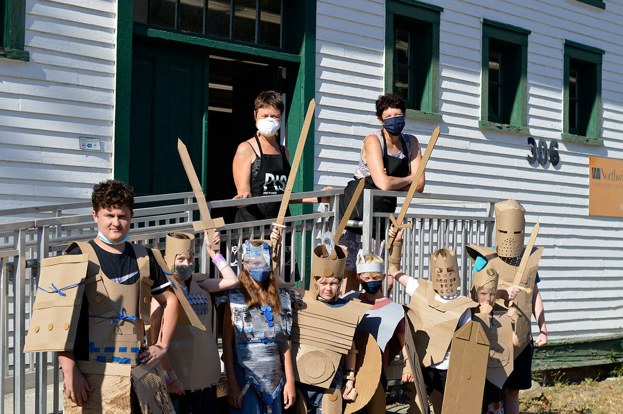 Teaching artists Margie McDonald, at left on the porch, and Michele Soderstrom led a four-afternoon course on building superhero armor for youngsters at the Northwind Art school at Fort Worden State Park in July. Their graduates are Callum Johnson, 14, Kaladry Groenig, Satria McKnight and Owen Griffith, all 11, Reid Armstrong, 10, Caleb Armstrong, 9, Byron Eisele, 8, and Nigel Groenig, 13. (Diane Urbani de la Paz/Peninsula Daily News)